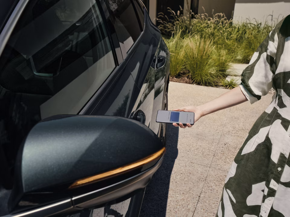 A woman using the Hyundai Digital Key 2 to unlock the driver's door of the Hyundai TUCSON Plug-in Hybrid.